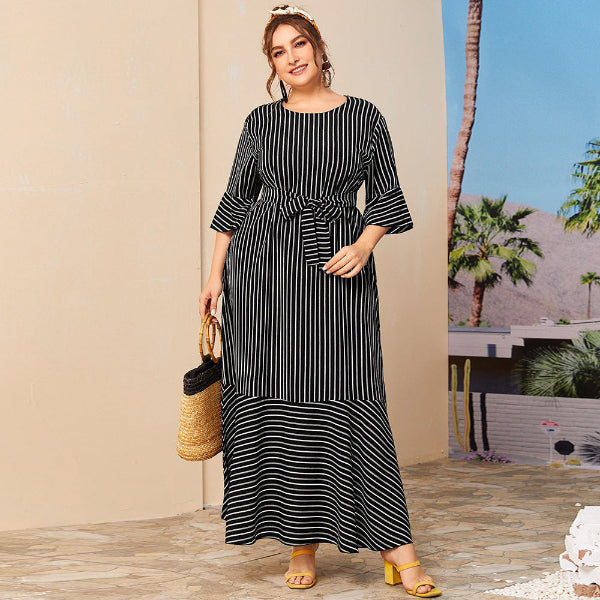 Woman wearing a black and white striped dress with a palm tree in the background