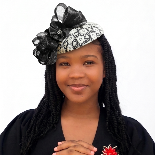 Woman with braided hair wearing a decorative headband and black top with a red flower brooch.