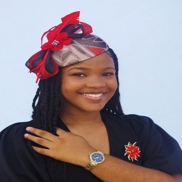 Young woman wearing a decorative headwrap with red accents against a light blue background