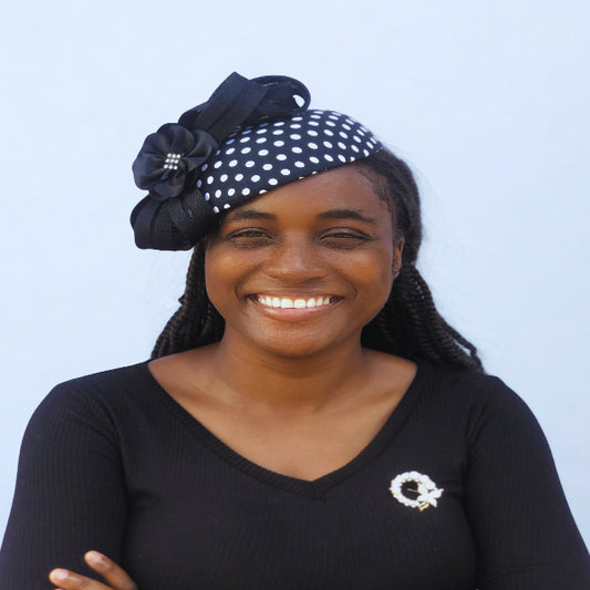 Woman wearing a black and white polka dot headband with a decorative bow against a light blue background