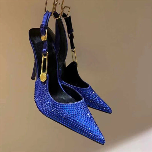 Blue studded high-heeled shoes with gold accents on a beige background