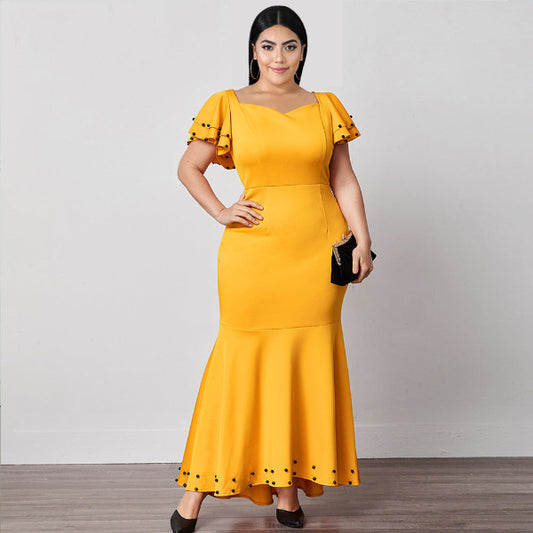Woman wearing a yellow dress with black polka dots on a plain background