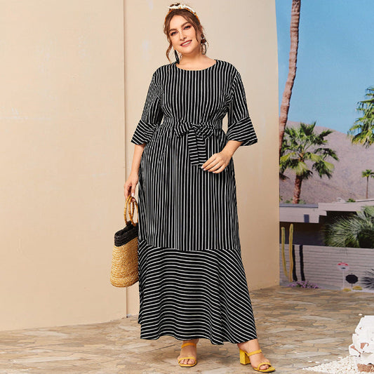 Woman wearing a black and white striped dress with a palm tree in the background