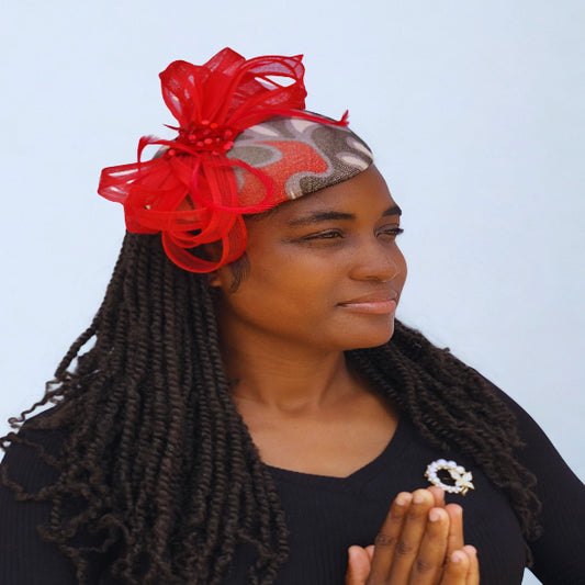 Woman wearing a red headpiece with a bow, holding a small decorative item against a light blue background