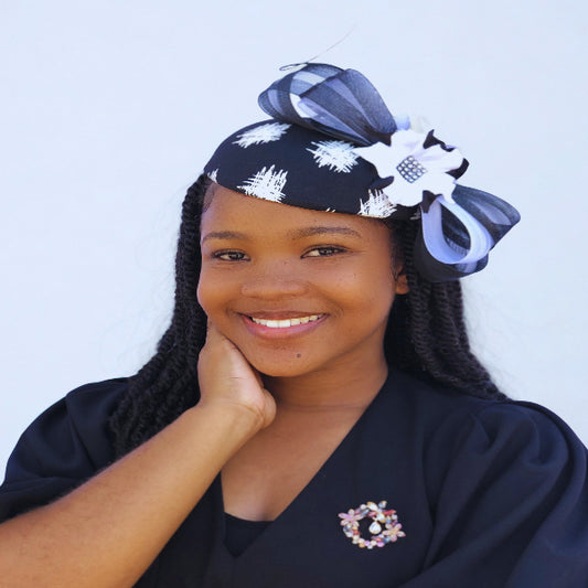 Woman wearing a black headwrap with white patterns against a light blue background