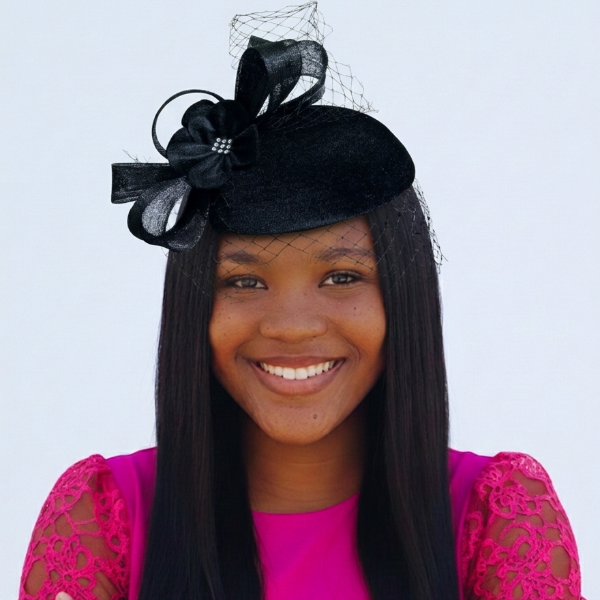 Woman wearing a black hat with a large bow against a light blue background