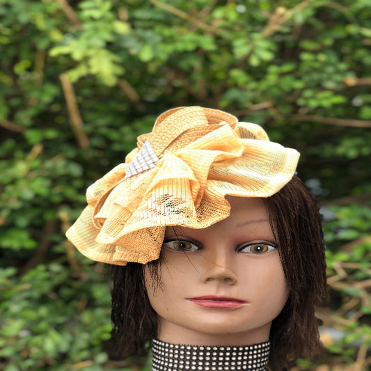 Mannequin head wearing a yellow decorative headpiece with a blurred green background