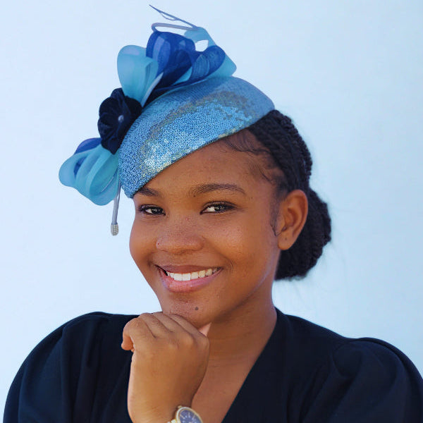 Woman wearing a blue decorative headpiece against a light blue background