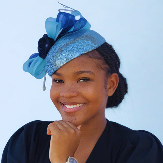 Woman wearing a blue decorative headpiece against a light blue background