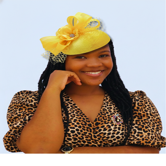 Woman wearing a yellow hat with a flower and leopard print top against a light blue background