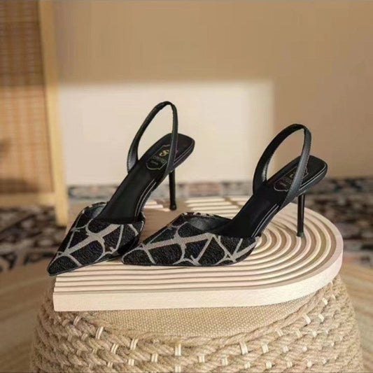 Black high-heeled shoes with a pattern on a wooden stool.