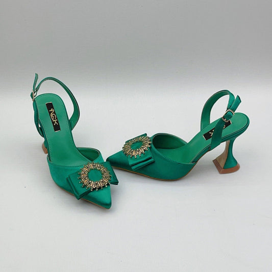 Green high-heeled shoes with decorative elements on a light gray background