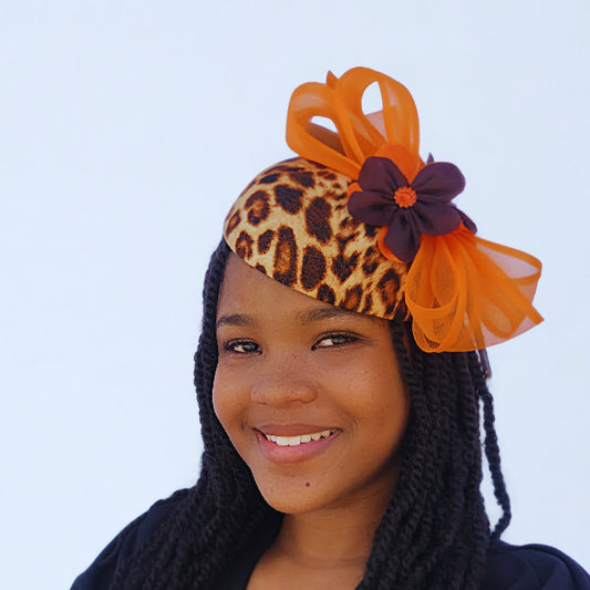 Woman wearing a decorative headpiece with orange and leopard print elements on a white background