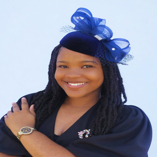 Woman wearing a dark blue headpiece with a large bow against a light blue background